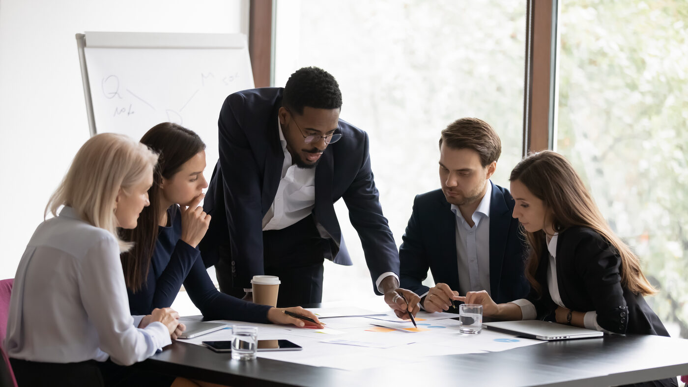A business leader reviewing project documents with a diverse professional team in a boardroom